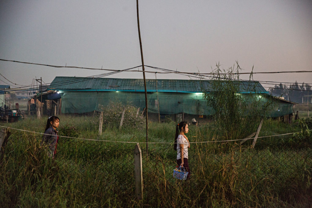 Garment factory workers walk down the footpath near their home on their way to work. The girls get a stipenf of 300 kyats ($0.25 USD) if they choose not to take the shuttle bus provided by their factory.