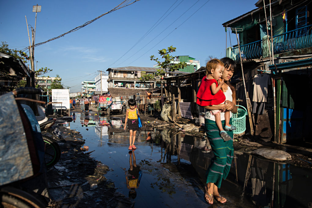 A woman and children walk down the flooded streets of Yangon's Hlaing Tharyar industrial Zone, an area that houses many garment factory workers.